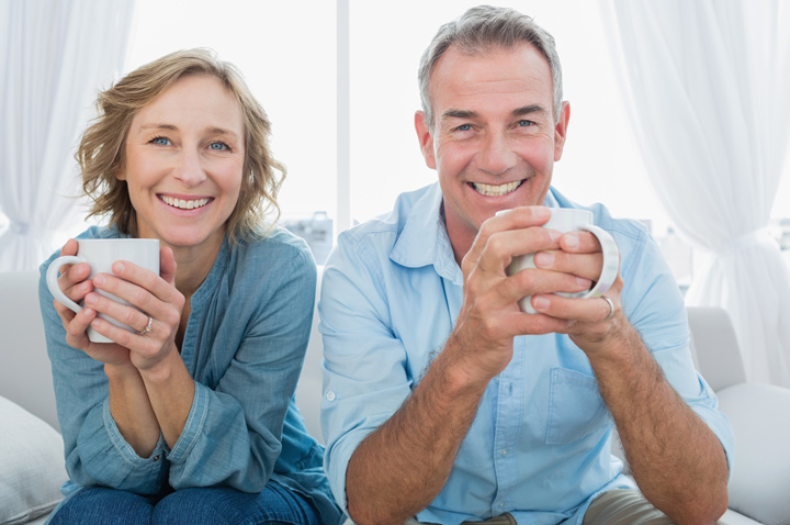 Over 55 Singles Smiling middle aged couple sitting on the couch